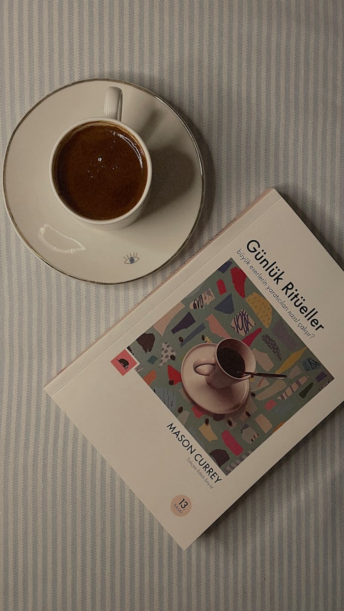 A cozy flat lay with a coffee and book on a striped surface, perfect for relaxation.